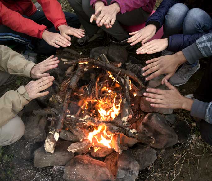 verschiedene Hände über Lagerfeuer zum wärmen